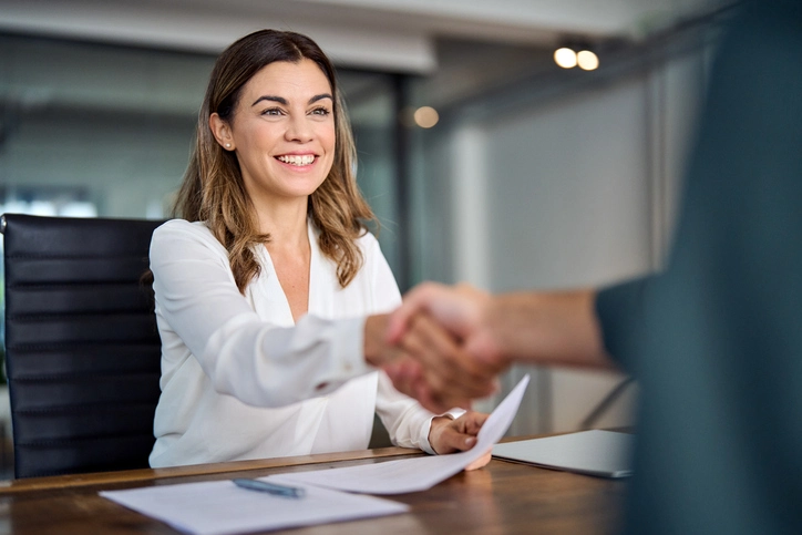 Female Attorney Shaking Hands With Client At Desk