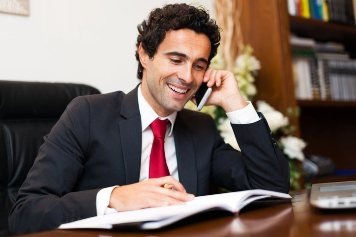 White Male Attorney On Phone With Client At Desk