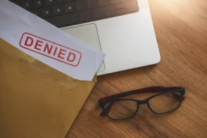 Denied Letter In Envelope On Top Of Laptop