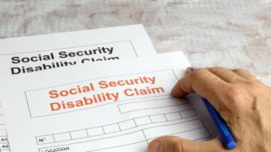 Social Security Disability Claim forms with a hand on top with pen
