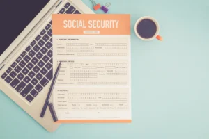 Social Security application form resting on a laptop next to a pen and cup of coffee, ready to be filled out.