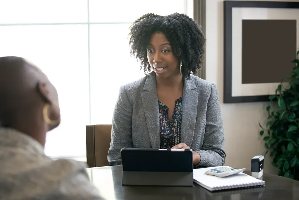 Disability attorney preparing a client across a desk with a tablet and notes before a hearing